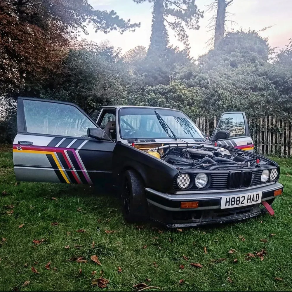 The E30 with the bonnet up, engine exposed.