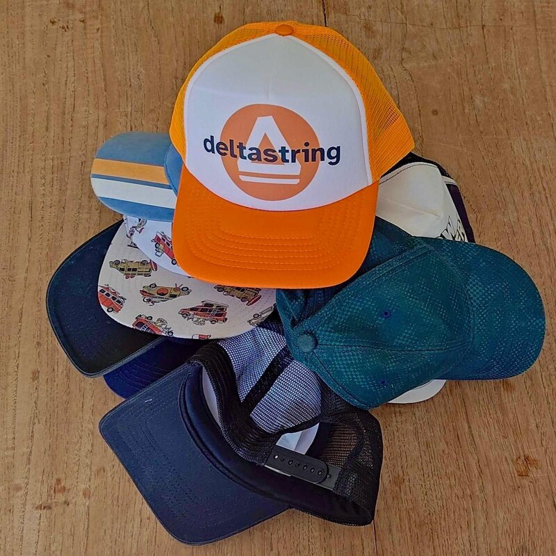 A stack of hats with a Deltastring cap on top